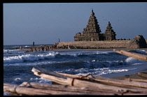 India, Tamil Nadu, Mamallapuram, Shore temple built in the late seventh century during the reign of  Rajasimha.  People on beach and wooden prows of boats in foreground.