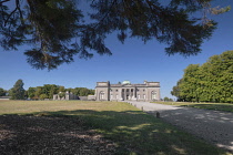 Ireland, County Laois, Emo Court, Facade of the house framed by overhanging tree branches, Emo Court is a quintessential neo-classical mansion designed by the famous architect James Gandon1790.