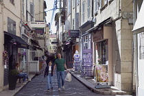 France, Provence-Alps, Cote d'Azur, Antibes, Narrow side street in the old town busy with shoppers.