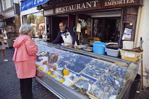 France, Provence-Alps, Cote d'Azur, Antibes, Woman buying shellfish from seafood brasserie in the old town.
