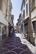 France, Provence-Alps, Cote d'Azur, Antibes, Narrow side street in the old town busy with shoppers.