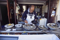 France, Provence-Alps, Cote d'Azur, Antibes, Fresh oysters being prepared outside seafood brasserie in the old town.