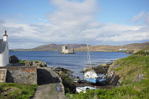 Scotland, Outer Hebrides, Isle of Barra, Castle Bay, Kisimul castle seen from the shore with moored boats in the foreground.