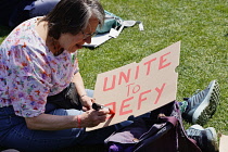 England, London, Westminster, Parliament Square, Protester making placard from cardboard with message to Unite to Defy.