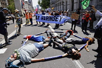 England, London, Westminster, Protesters marching outside Downing Street lying on ground linking arms.