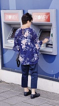 Finance, Banks, Money, Woman using ATM in high street to withdraw cash.