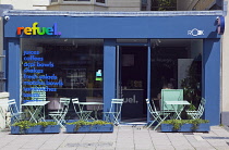 England, East Sussex, Brighton, Hove, Western Road, Refuel healthy cafe with metal tables outside.