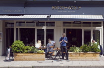 England, East Sussex, Brighton, Hove, Western Road, Brod + Wolf Organic bakery and cafe with tables outside.