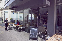 England, East Sussex, Brighton, Hove, Western Road, Waitress clearing table outside Nord cafe.