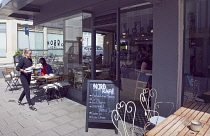 England, East Sussex, Brighton, Hove, Western Road, Waitress clearing table outside Nord cafe.