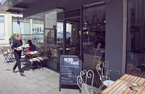 England, East Sussex, Brighton, Hove, Western Road, Waitress clearing table outside Nord cafe.