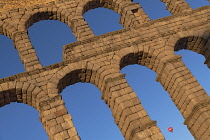 Spain, Castile and Leon, Segovia, Hot air balloon gliding past as early morning golden light shines on the Aqueduct of Segovia, a Roman aqueduct with 167 arches built around the first century AD to ch...