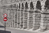 Spain, Castile and Leon, Segovia, Traffic signs with the Aqueduct of Segovia, a Roman aqueduct with 167 arches built around the first century AD to channel water from springs in the mountains 17 kilom...