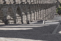 Spain, Castile and Leon, Segovia, Evening light streaming through the arches of the Aqueduct of Segovia, a Roman aqueduct with 167 arches built around the first century AD to channel water from spring...