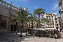 Spain, Balearic Islands, Majorca, Palma de Mallorca, Old Town. Placa de La Llotja. People at restaurant table under umbrellas in the old market square.