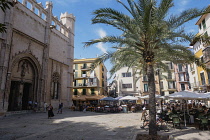 Spain, Balearic Islands, Majorca, Palma de Mallorca, Old Town. Placa de La Llotja. People at restaurant table under umbrellas in the old market square.