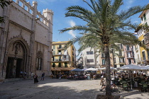 Spain, Balearic Islands, Majorca, Palma de Mallorca, Old Town. Placa de La Llotja. People at restaurant table under umbrellas in the old market square.