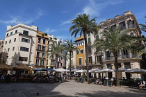 Spain, Balearic Islands, Majorca, Palma de Mallorca, Old Town. Placa de La Llotja. People at restaurant table under umbrellas in the old market square.