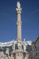 Austria, Tyrol, Innsbruck, Annasaule or St Anne's Column on Maria Theresien Strase dating from 1706 with snow covered mountains in the background.