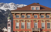 Austria, Tyrol, Innsbruck, Altstadt, colourful street architecture with the Servitenkirche or Servite Church and snow covered mountains in the background.