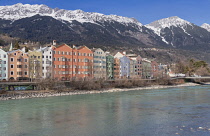 Austria, Tyrol, Innsbruck, Inn river with colourful modern houses and the snow clad Tyrolean Alps on the other side of the river.