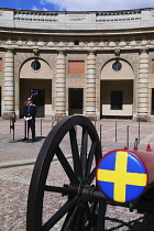 Sweden, Stockholm, Royal Palace guard beside canon with Swedish emblem on the barrel.