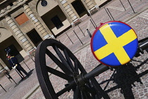 Sweden, Stockholm, Royal Palace guard beside canon with Swedish emblem on the barrel.