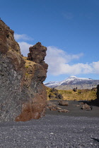 Iceland, Snaefellsnes Peninsula National Park, Djupalonssandur black sand beach. Rock formations with Snaefellsjokull, a 700,000-year-old glacier-capped stratovolcano in the distance.