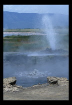 Kenya, Lake Bogoria, Spouting water from a hot spring with bubbling water in a pool in the foreground.