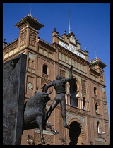 Spain, Madrid, Plaza de Toros de Las Ventas.  Angled view of exterior of bullring with statue of bull and matador in the foreground.