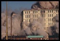 Architecture, Demolition, Clouds of dust cloud rising from building that is being demolished using explosive charges.