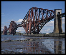 Bridges, Iron, Scotland, The Forth Rail Bridge.  The west side seen from South  Queensferry and reflected in shallow water in the foreground.