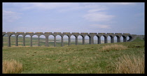 England, North Yorkshire, Ribble Head, Viaduct in rural landscape with north bound Agregate train crossing.