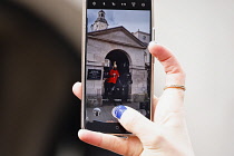 England, London, Westminster, Whitehall, member of the Household Cavalry on horseback being recorded on mobile phone.