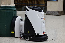 England, London, Charring Cross Railway Station, Automated robotic floor cleaner being recharged on the station concorse, Fitted with sensors to detect people and obstructions.