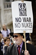 England, London, Well dressed gentleman and member of CND holds a plackard against Nuclear weapons and war during a palestinian anti-war protest outside the Houses of Parliment.