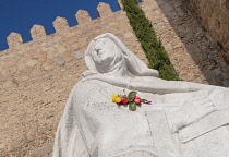Spain, Castile and Leon, Avila, City walls that were built from 1090 onwards and are among the best-preserved and most complete in Europe with a white statue of Saint Teresa of Avila in the foreground...