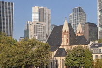 Germany, Hesse, Frankfurt, St Leonhard's Roman Catholic church with the towers of the Financial District in the background seen from the Eiserner Steg bridge, it was the only one of nine churches in t...