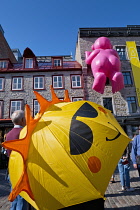 Canada, Quebec Province, Quebec City, Quebec Old City or Vieux Quebec, in Basse-Ville or Lower Town. Tourist with Smiley umbrella in Place Royale looking at one of the inflatable Mr Pink, or Monsieur...
