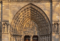 France, Paris, Cathedral de Notre Dame, West facade in golden evening light, detail of the main entrance portal with carving of the Last Judgement.