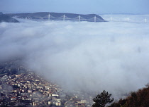 France, Aveyron, View west above  the town of Millau with Viaduc de Millau fog covered bridge.