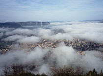France, Aveyron, View west above  the town of Millau with Viaduc de Millau fog covered bridge.
