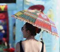 England, Hampshire, Eastleigh, Wickham Festival, Reveller taking shade under a parasol.