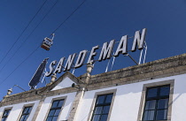 Portugal, Porto, Vila Nova de Gaia, The Teleférico de Gaia aerial gondola in motion high above the Sandeman sign and logo on the Sandeman Port Building  which is a granite building dating from 1811.