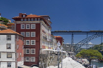 Portugal, Porto, Facades on the heavily touristed Ribeira waterfront with a tram crossing Dom Luis I Bridge or Ponte de Dom Luis I.