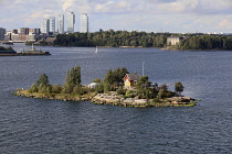 Finland, Helsinki, House on small island on approach to Helsinki, High rise suburb of Kalasatama in the background